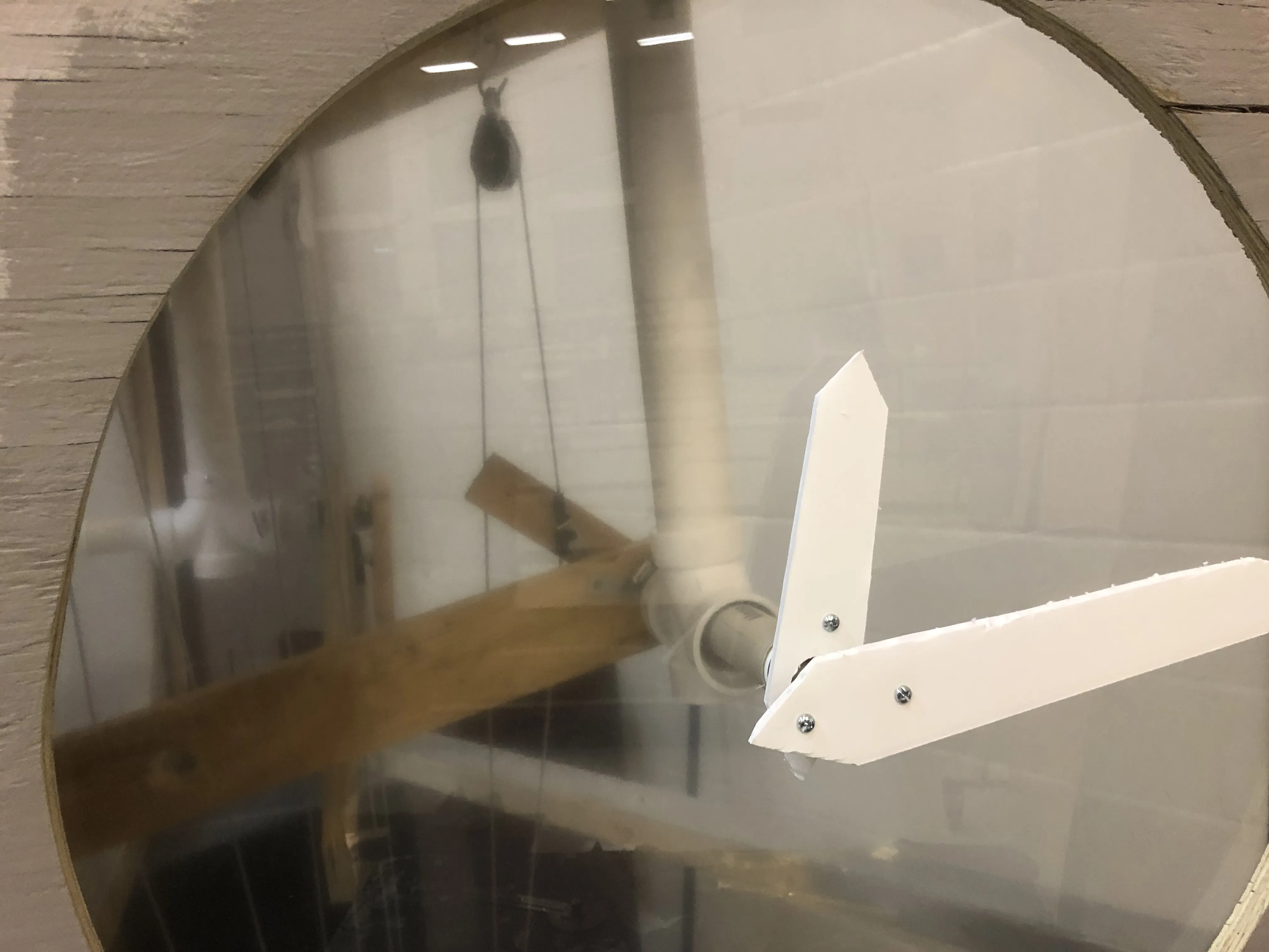 Through the plexiglass — the wooden frame, cables, and counterweight system visible behind the face