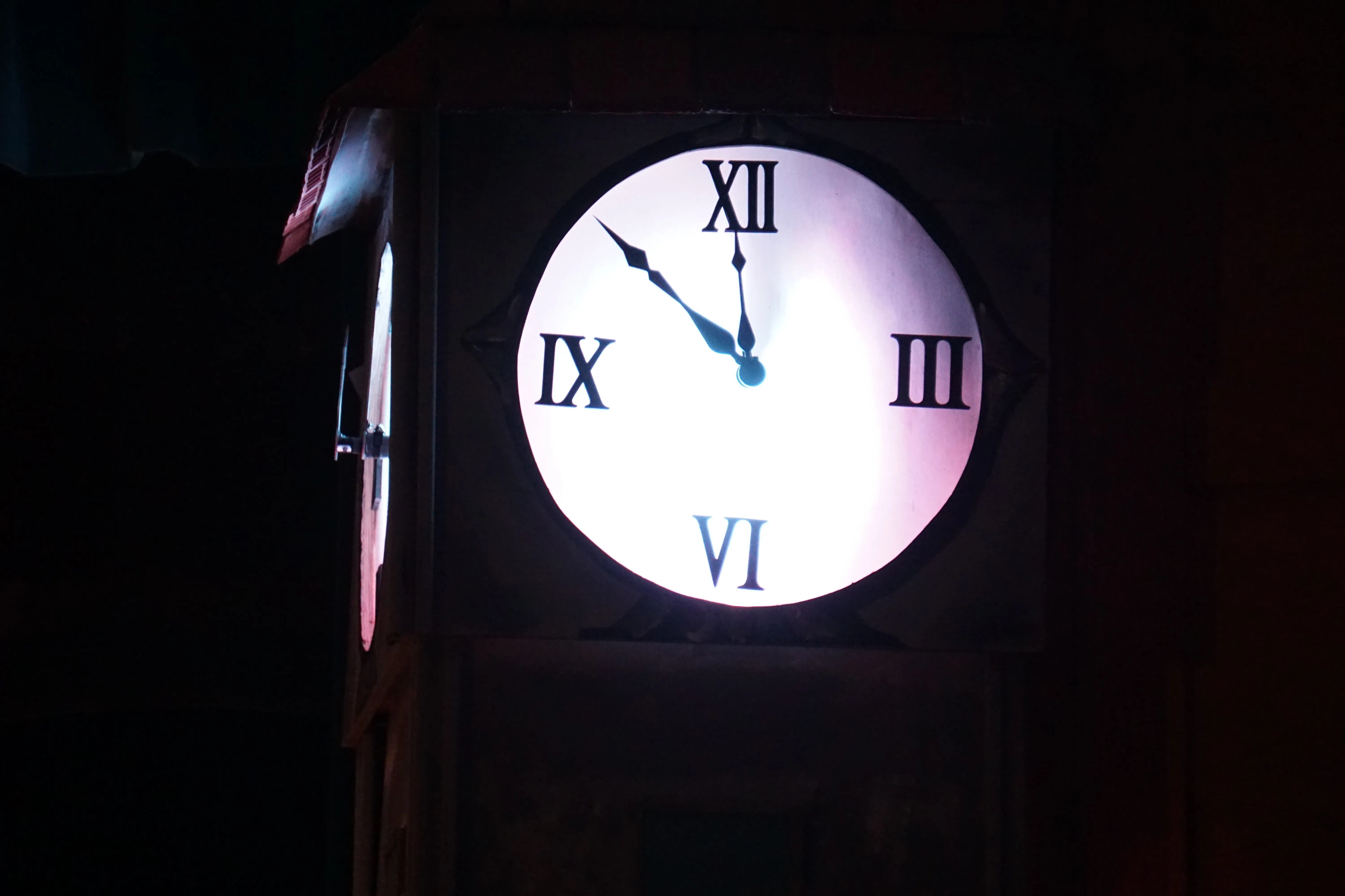 The clock face at midnight — both hands at XII, glowing brilliant white