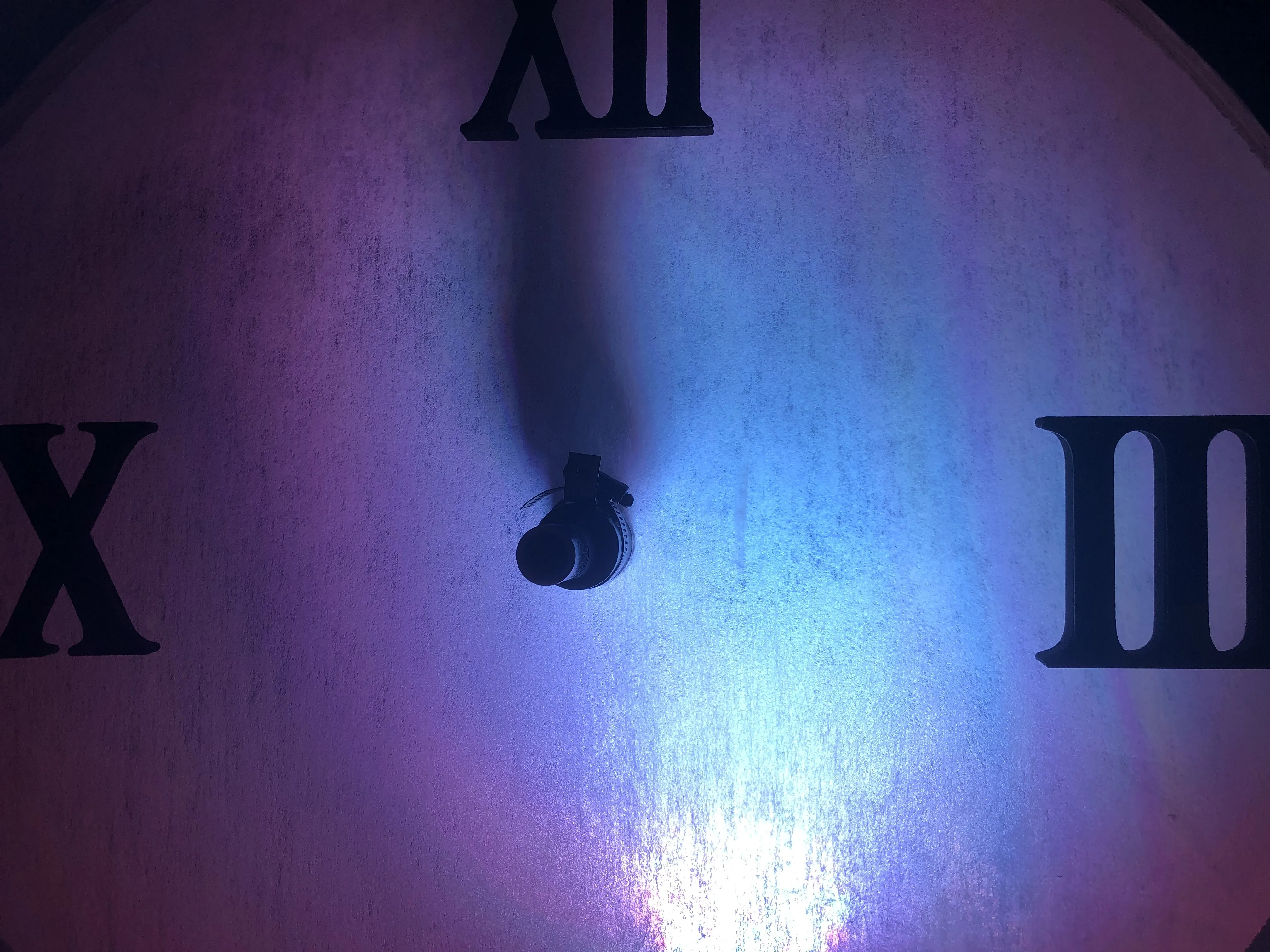 The clock face glowing with purple and blue colored light — the tension of approaching midnight
