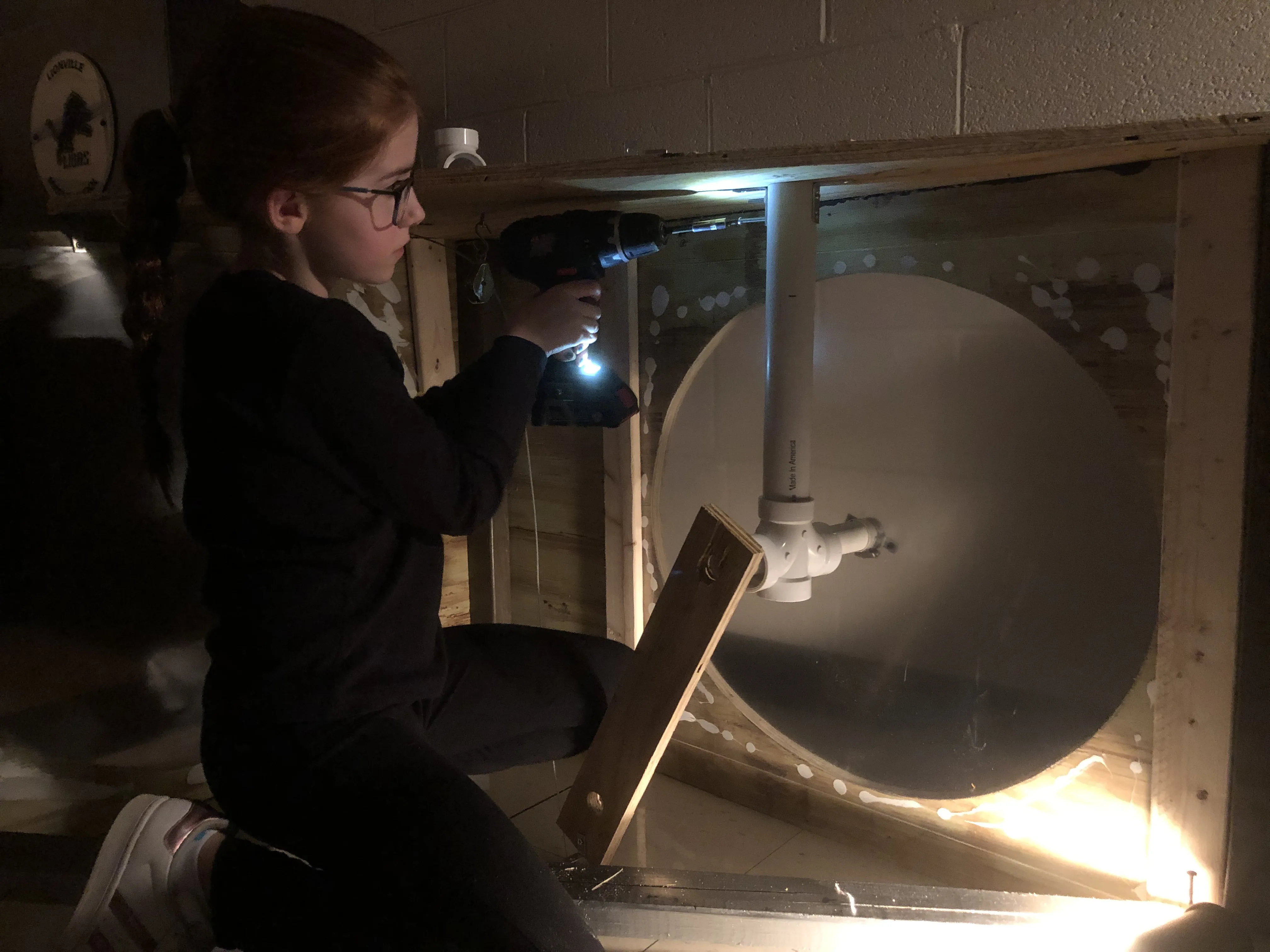 A crew member working inside the clock box with a drill during assembly