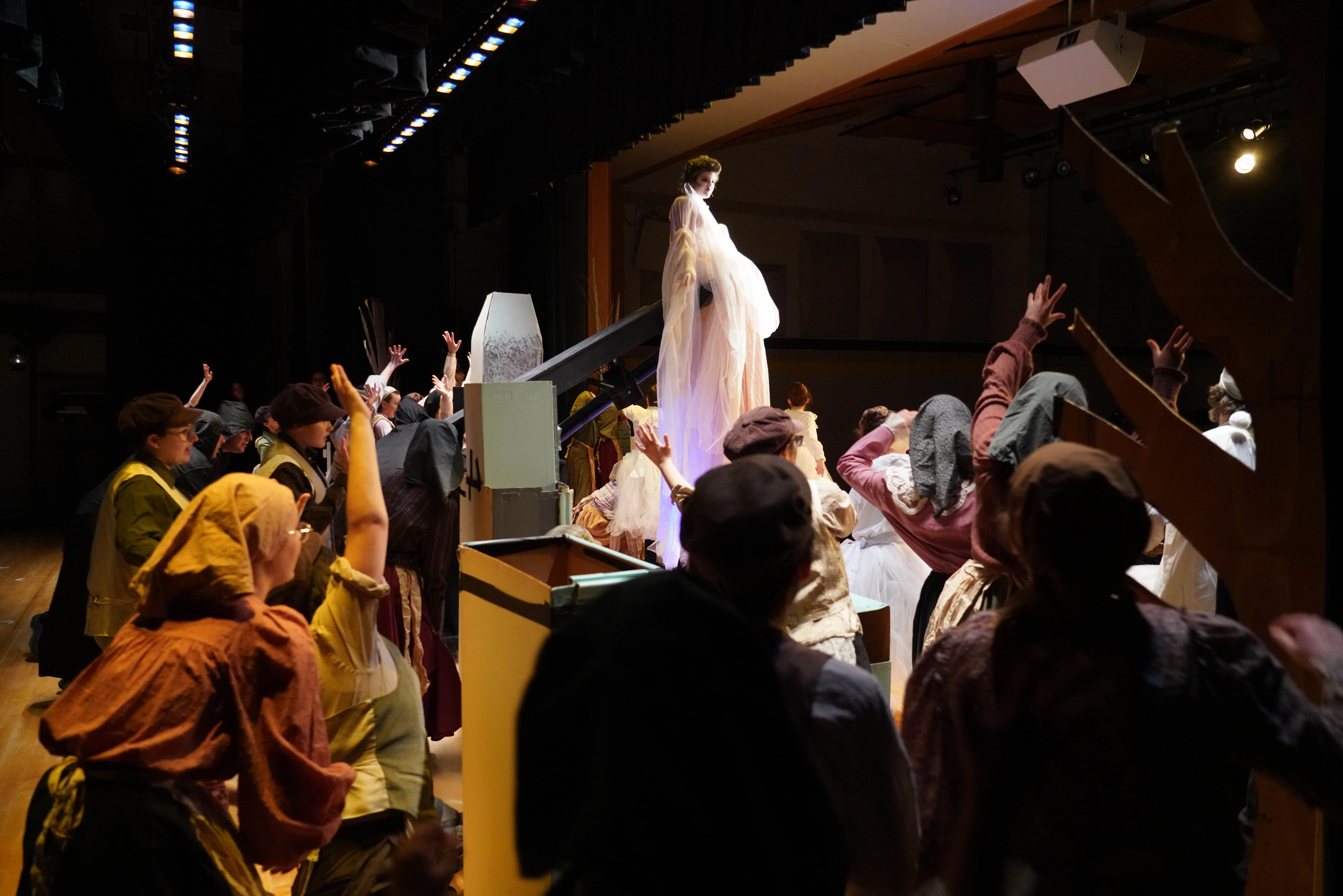 Wide shot of the full dream scene — Fruma-Sarah elevated, ghost ensemble, fog, and Tevye in bed