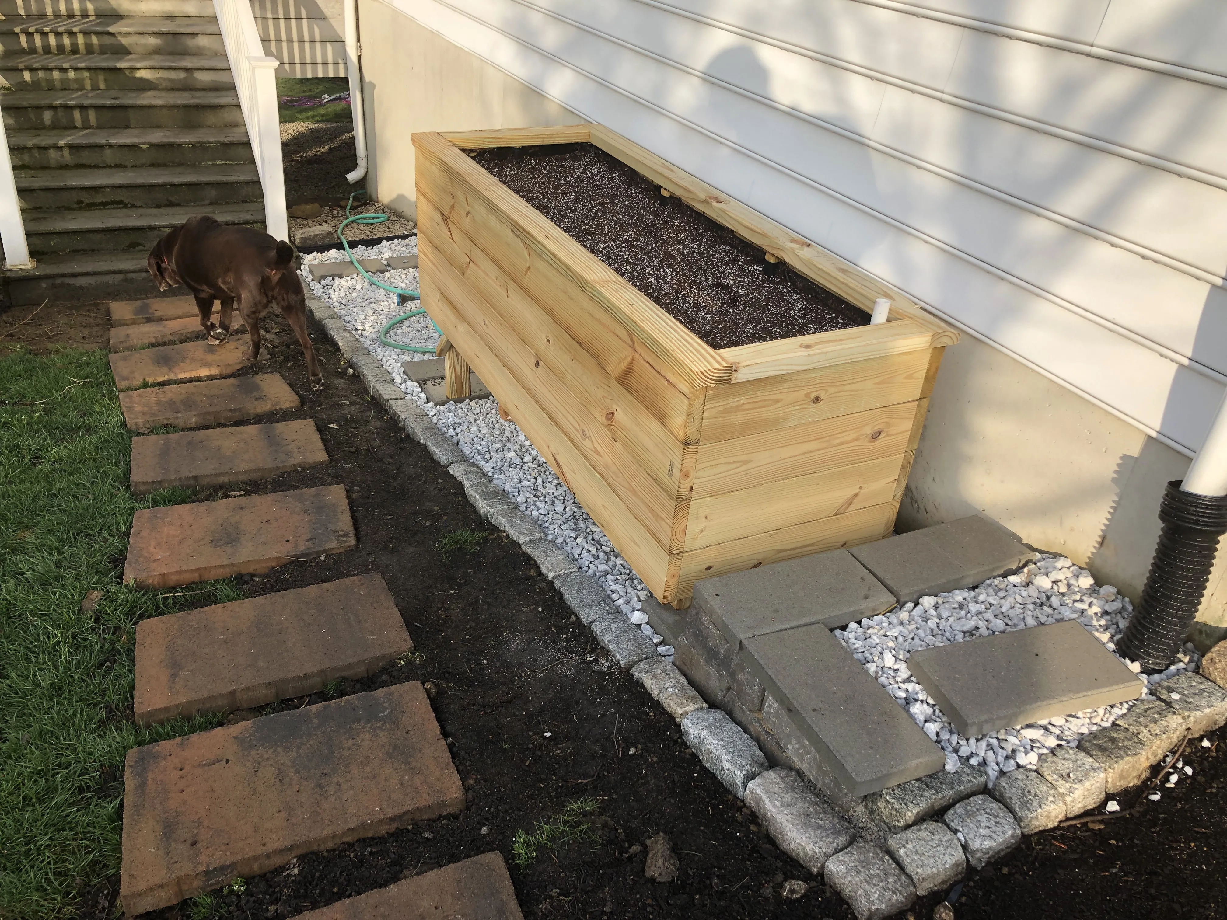 The finished beds — cedar on legs, gravel surround, brick stepping stones