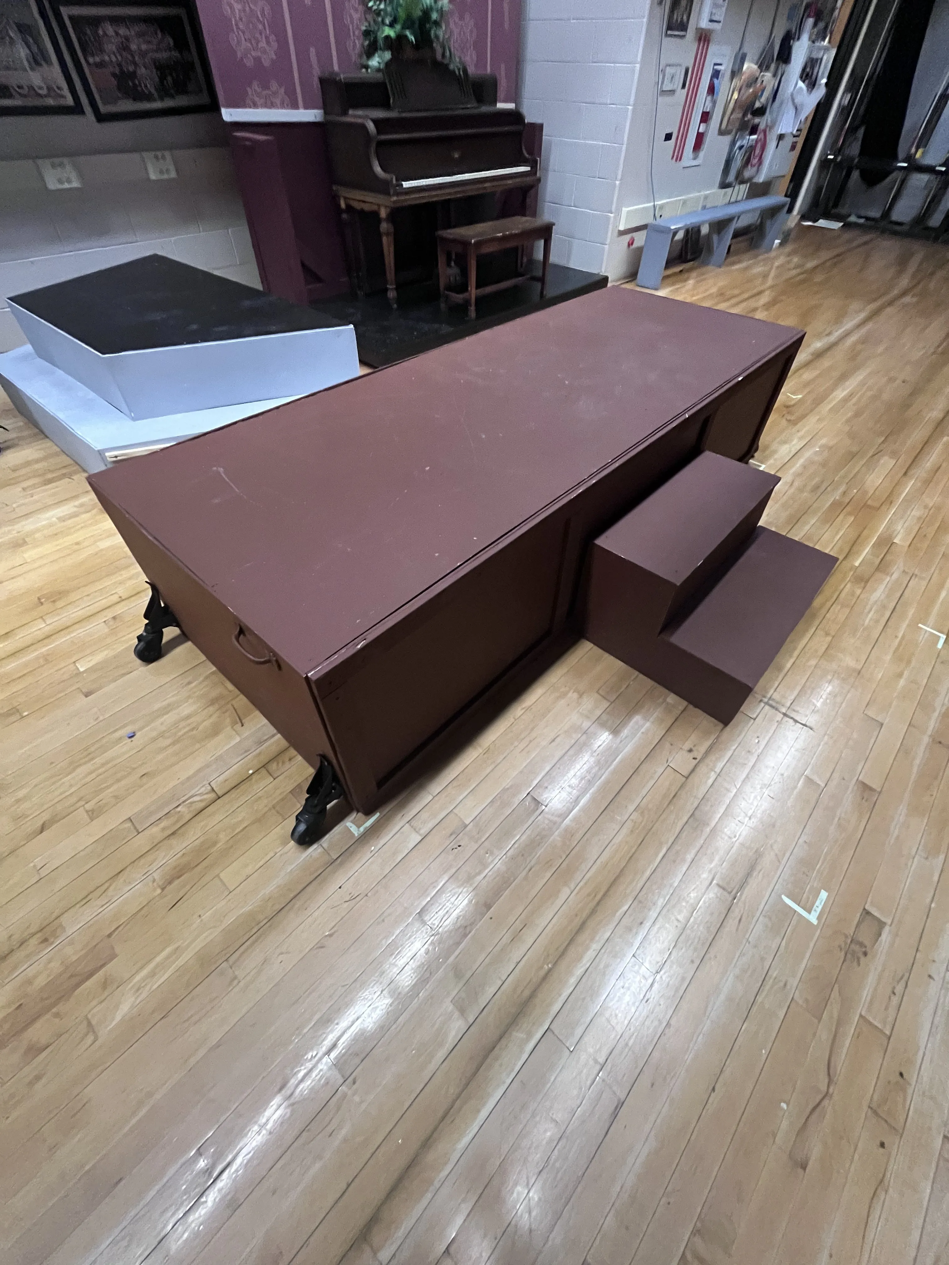 The library desk box and piano set up in the cafeteria before the show — Stephanie's wallpaper flat visible in the background